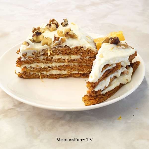 Low-carb carrot cake for one fried on a non-stick skillet with ricotta cheese icing, topped with walnuts on a white plate.